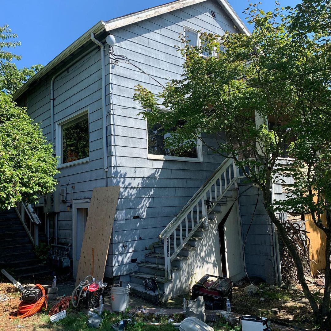 A small house with stairs leading up to it is surrounded by trees.