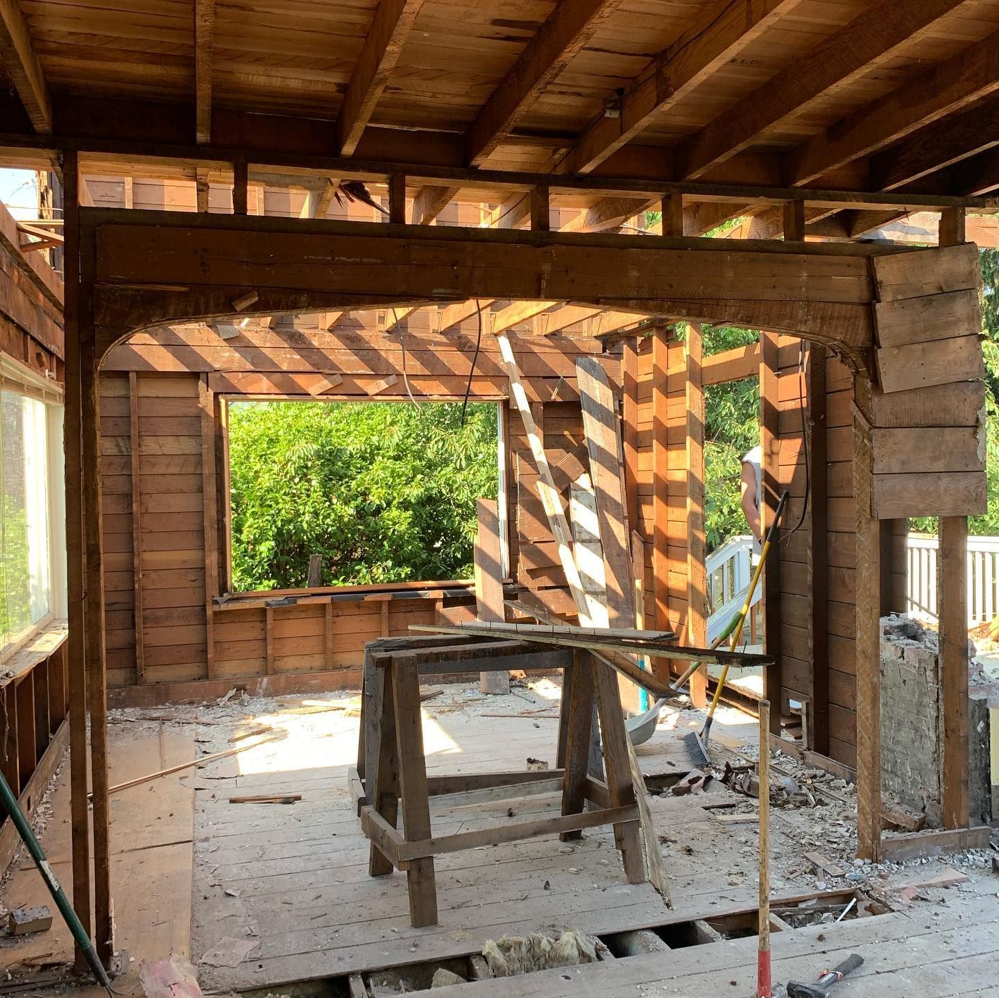 A wooden structure is being demolished with a window in the middle