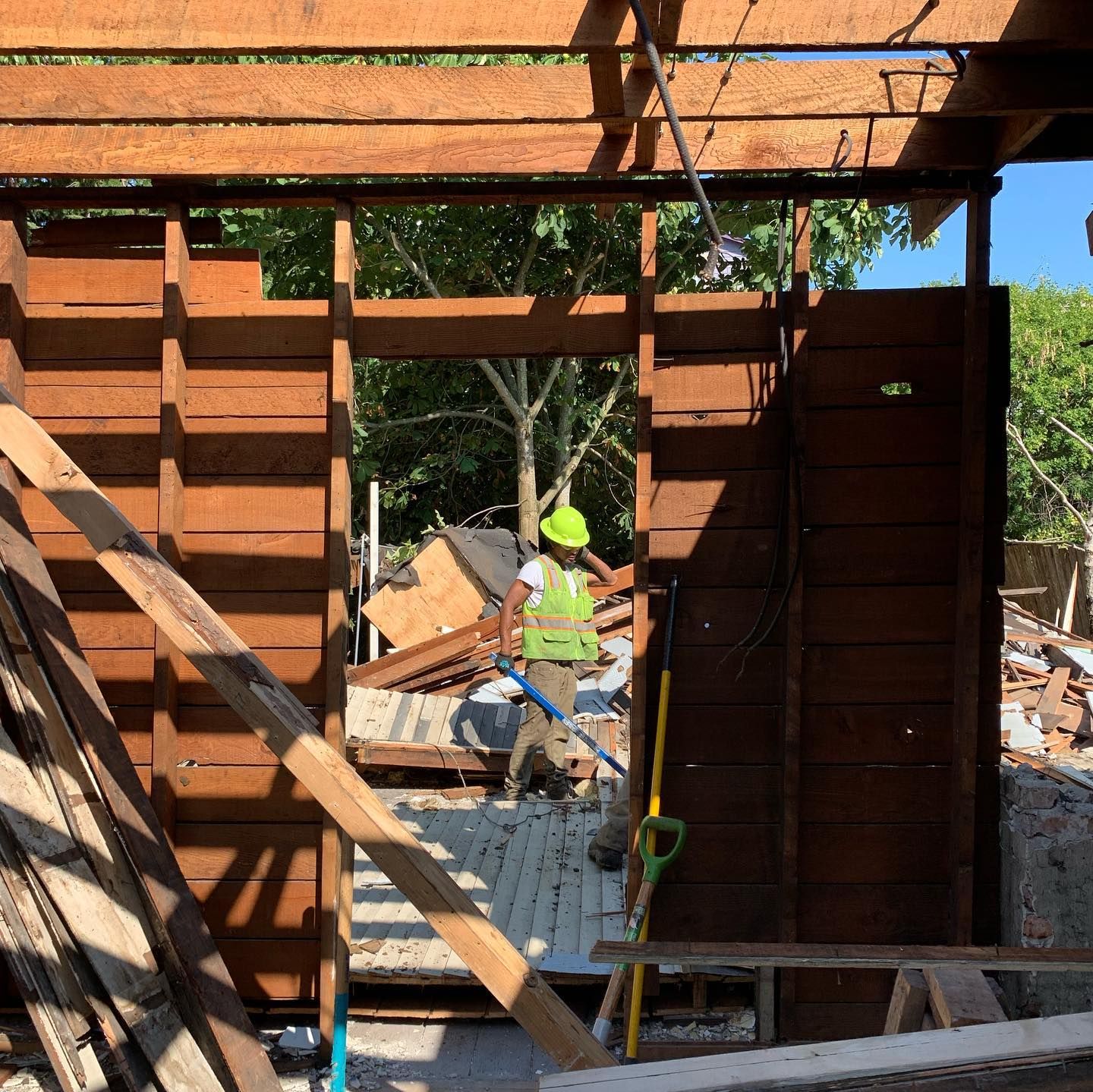 A man wearing a hard hat and safety vest is working on a wooden structure