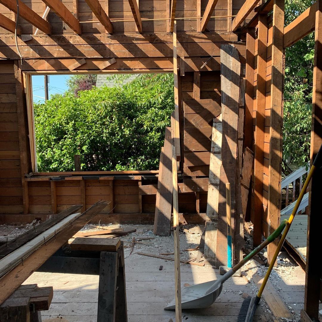 A wooden building under construction with a window and a shovel.