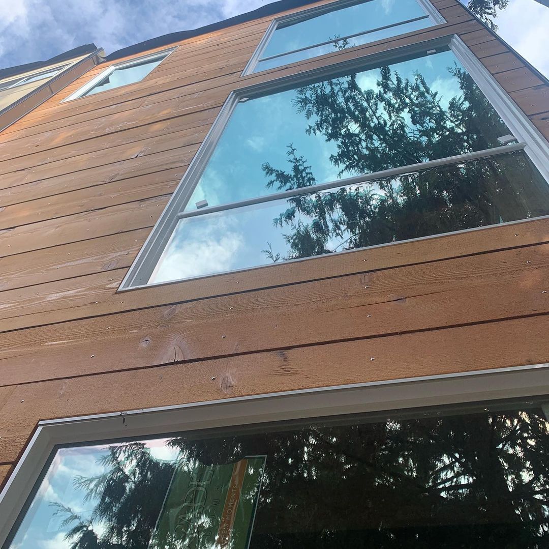 A building with a lot of windows and trees reflected in the windows.