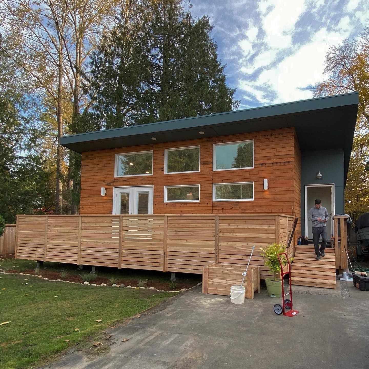 A man is standing in front of a wooden house