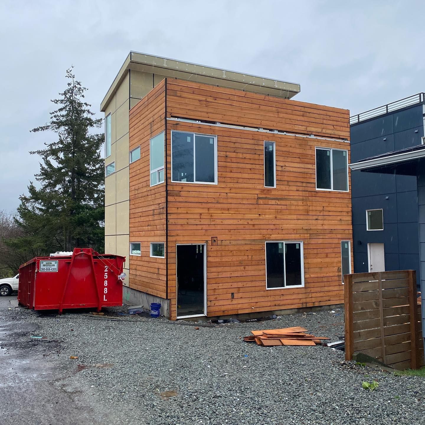 A building under construction with a red dumpster in front of it
