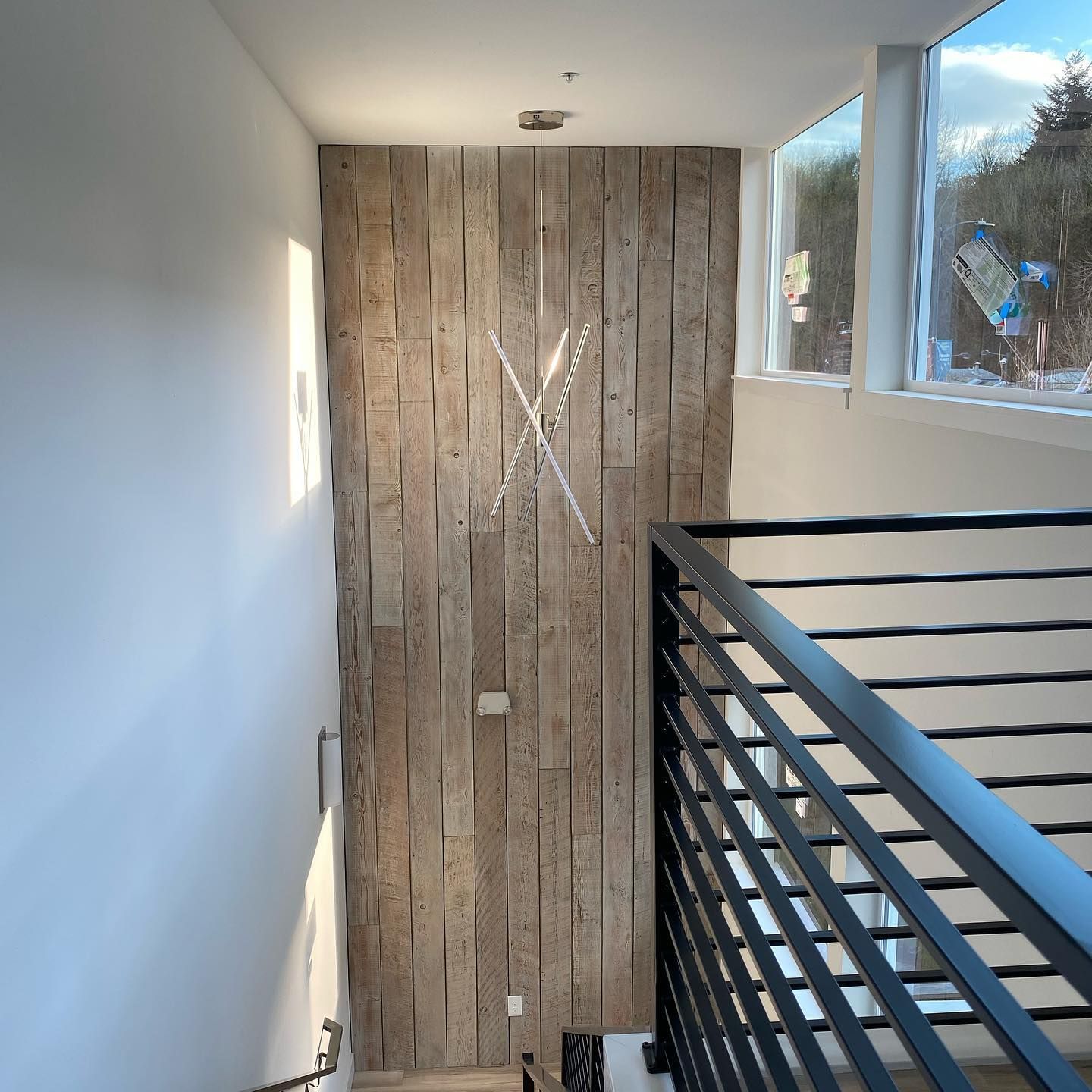 A staircase with a wooden wall and a black railing