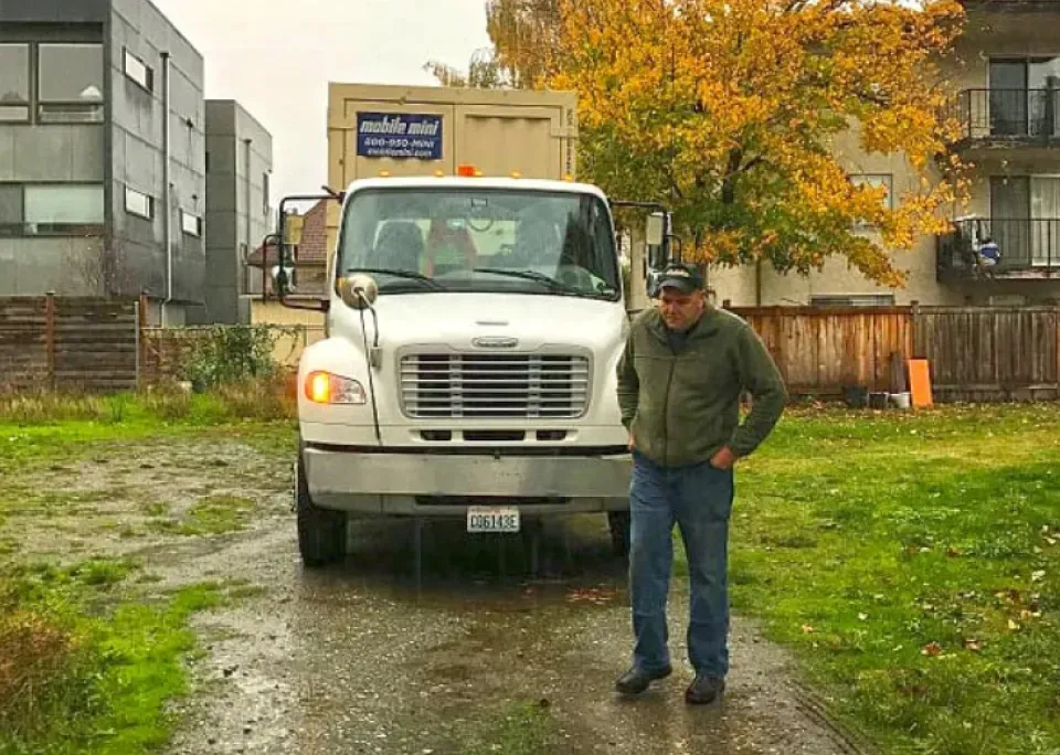 A man is standing in front of a white truck.