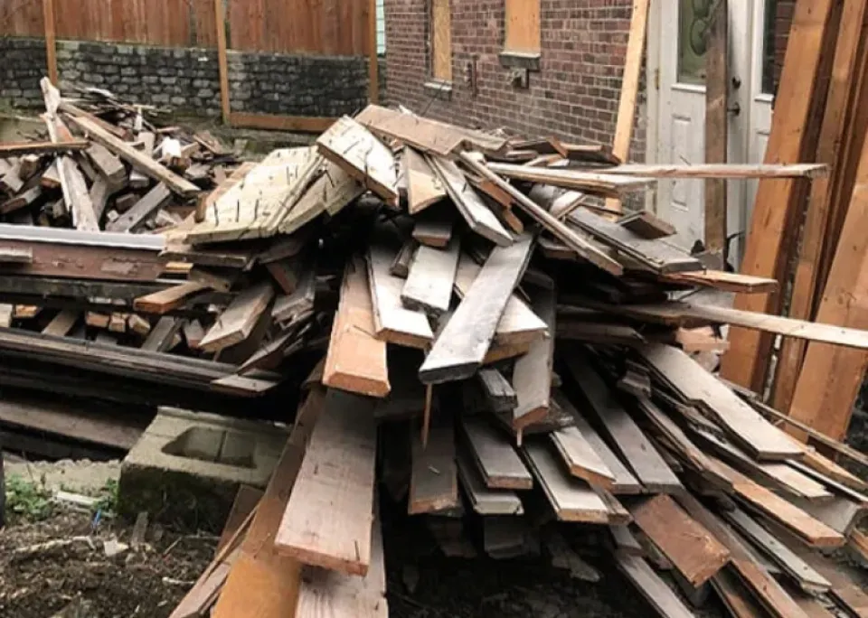 A pile of wood is sitting in front of a brick building.