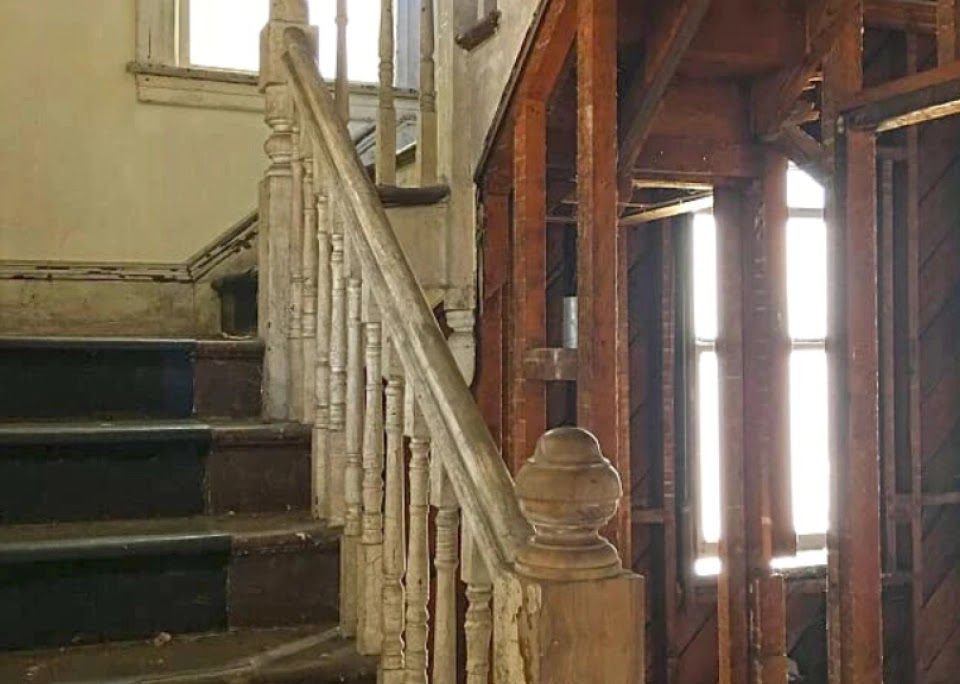 An old wooden staircase in a house under construction.