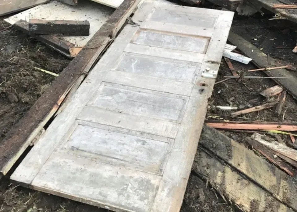 A wooden door is laying on top of a pile of wood.