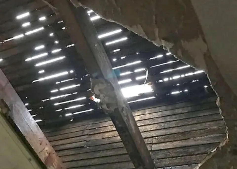 A hole in the ceiling of a building with a light shining through it.