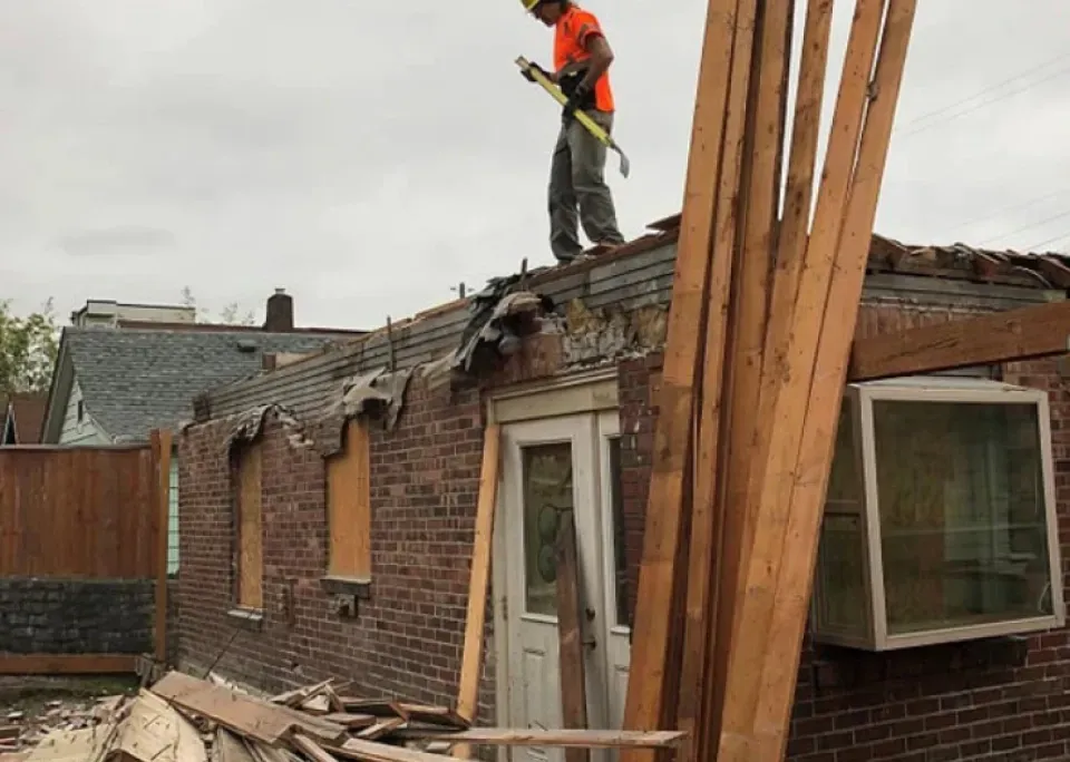 A man is standing on the roof of a brick building.