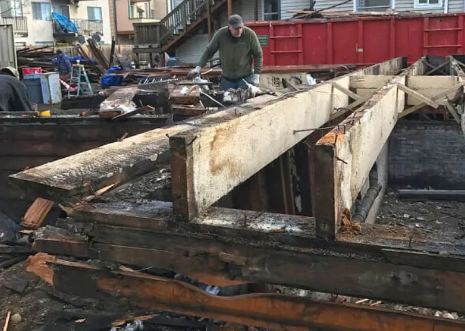 A man is standing on a pile of wood.