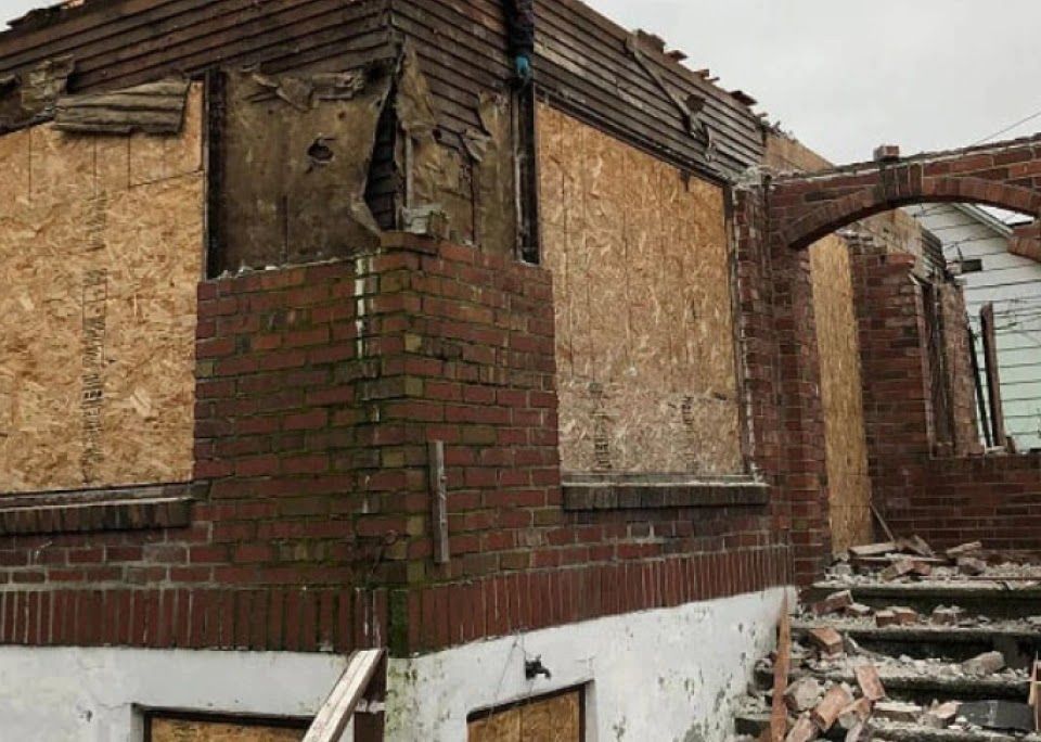 A brick building with a chimney and stairs is being demolished.