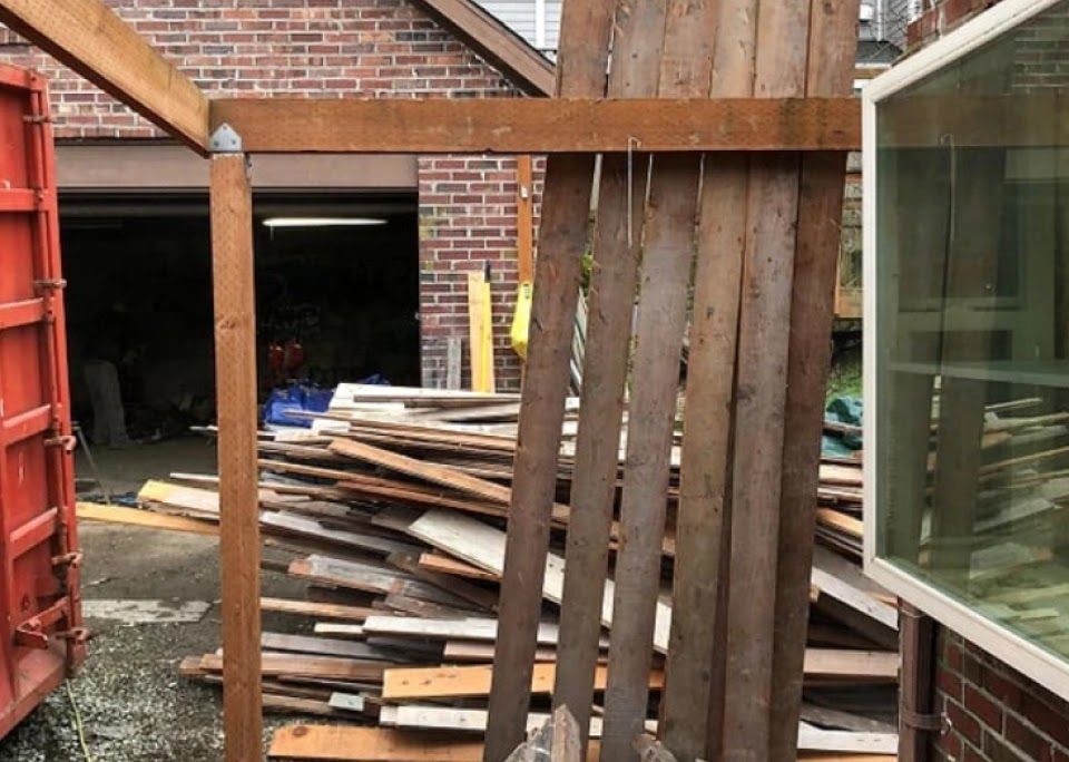 A pile of wood is sitting in front of a brick building.