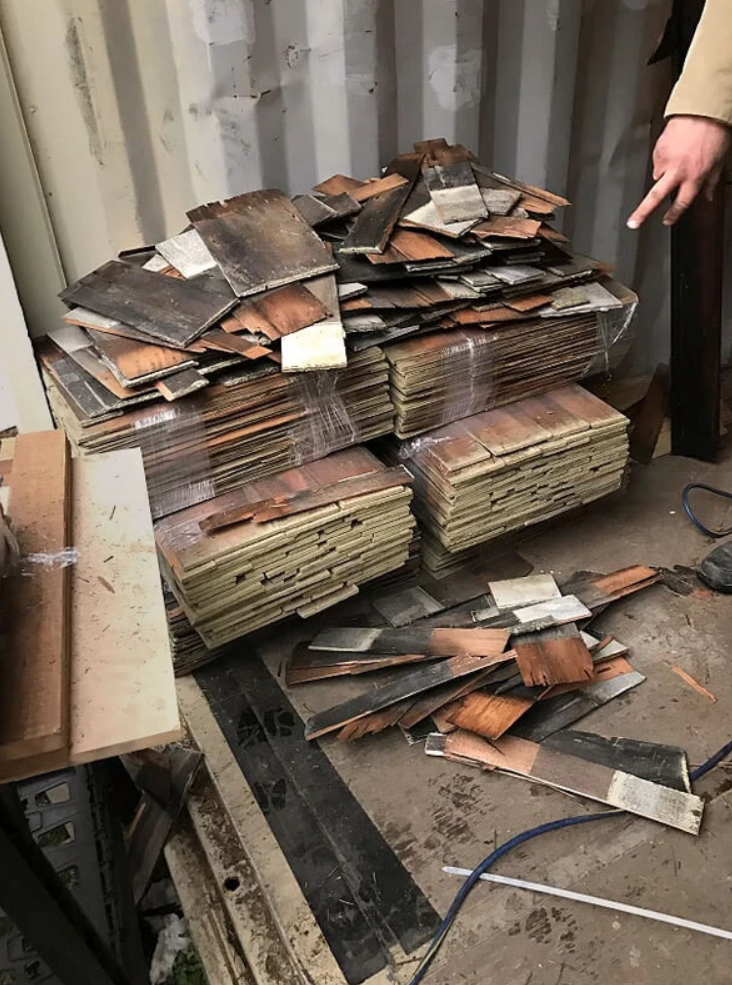 A person is standing next to a pile of wood.