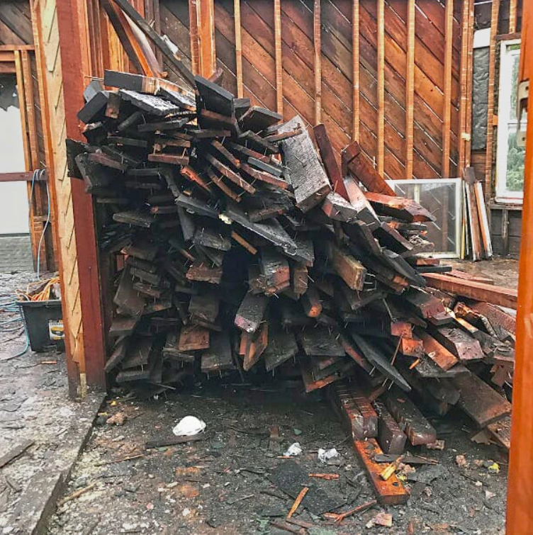 A pile of wood is sitting in front of a building under construction.