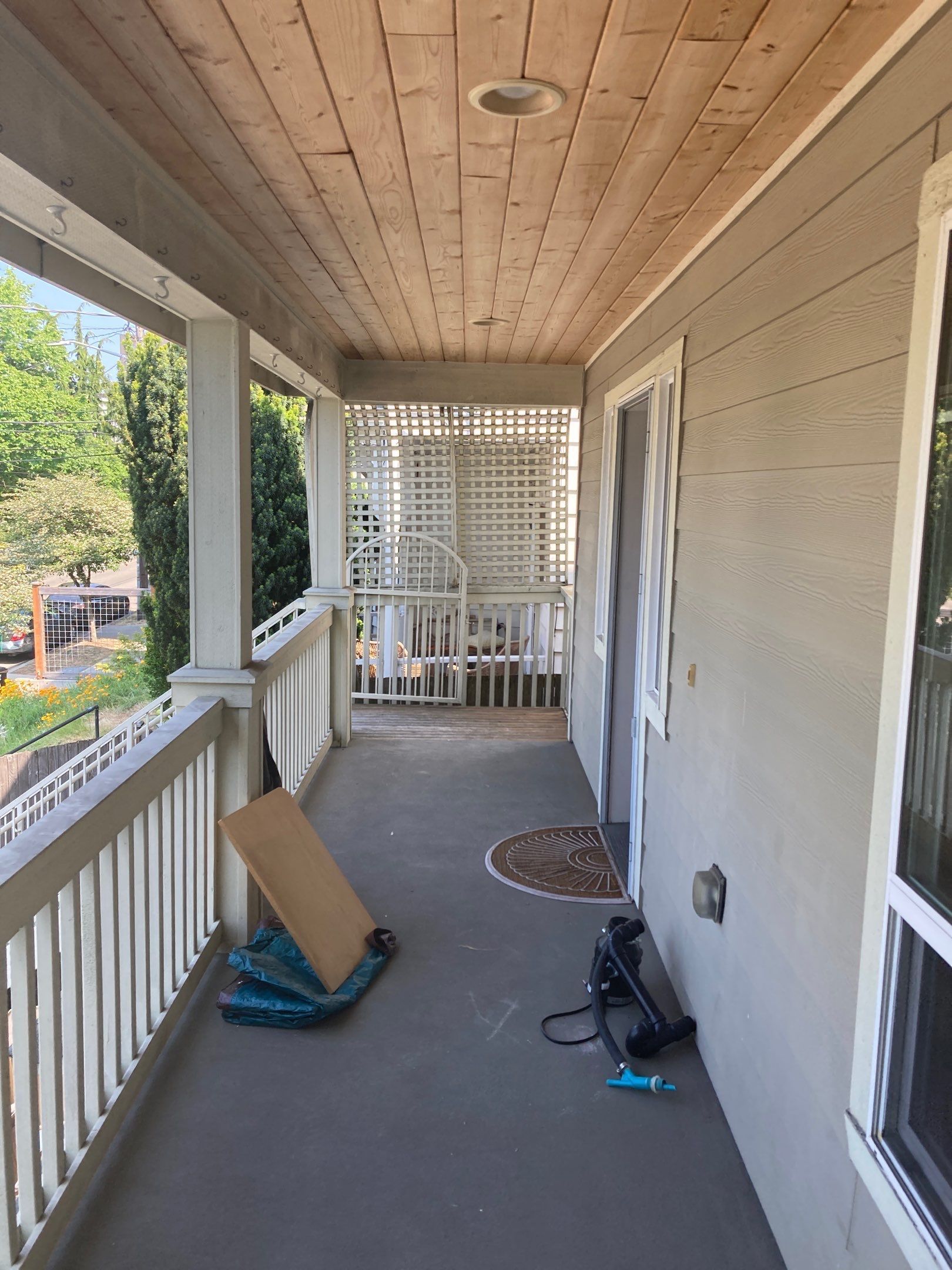 A porch with a wooden ceiling and a white railing.