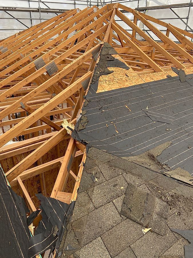 The roof of a building is being built with wooden beams and shingles.