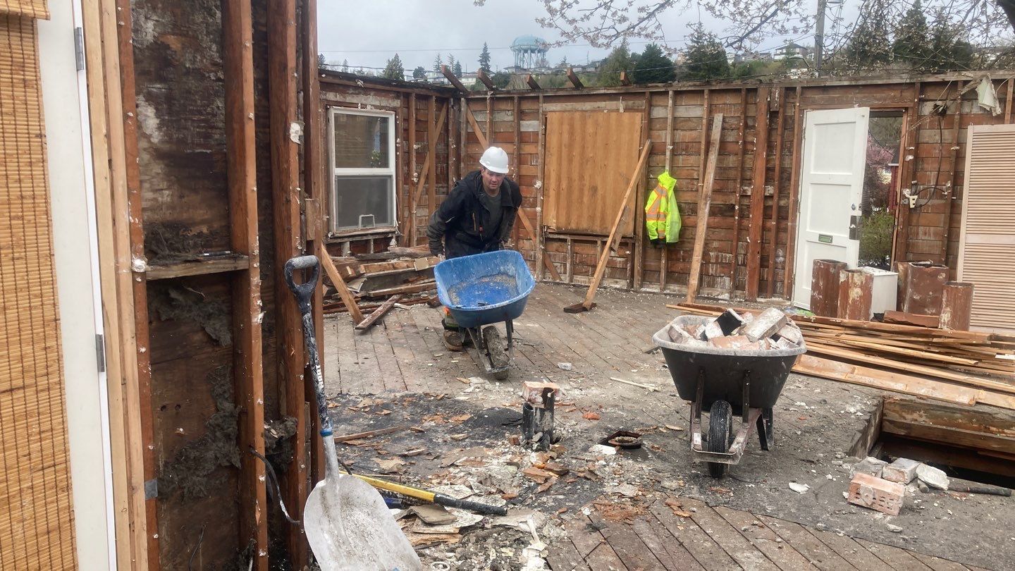 A man is pushing a wheelbarrow full of wood.