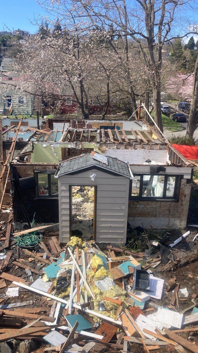 A shed is sitting in the middle of a pile of rubble.