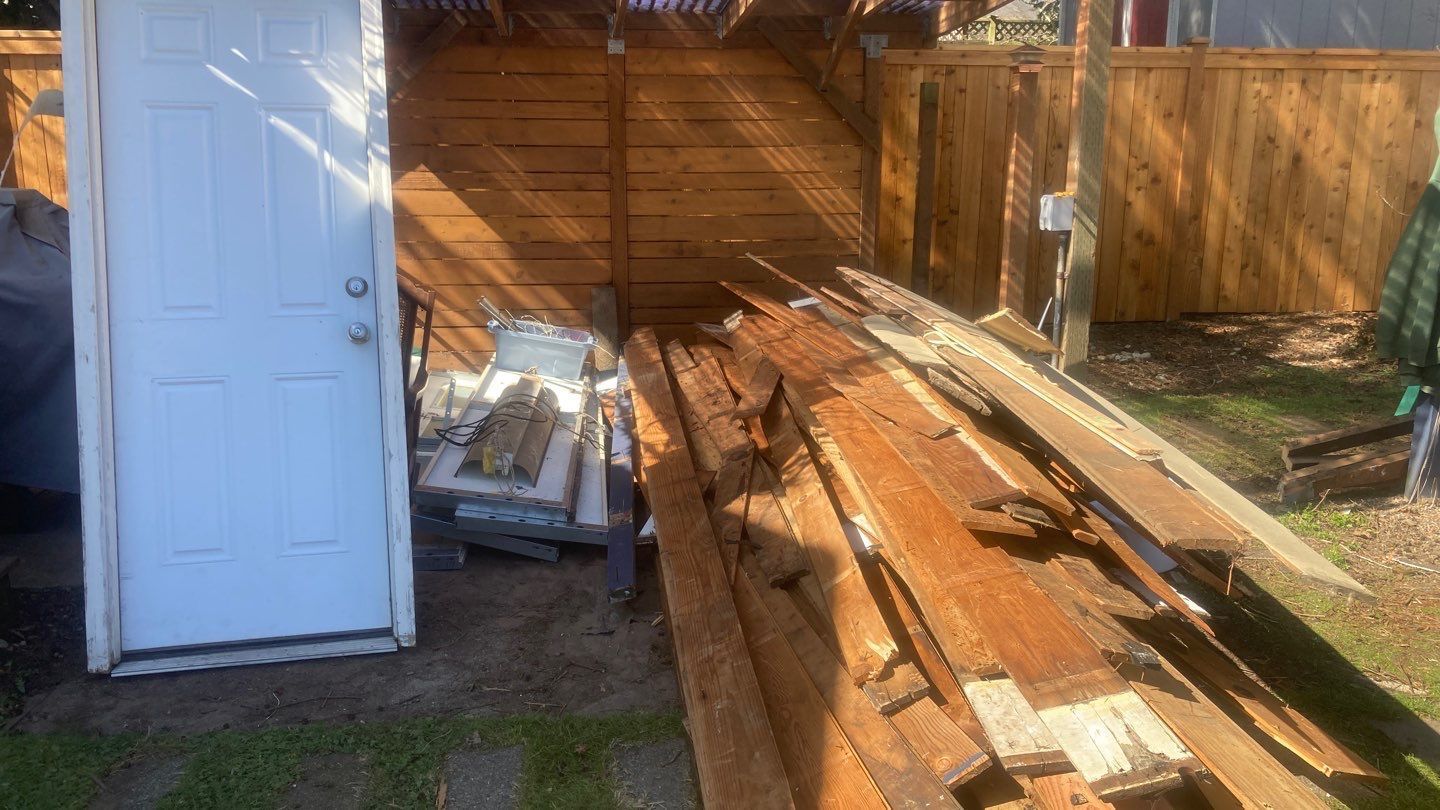 A white door is sitting next to a pile of wood.