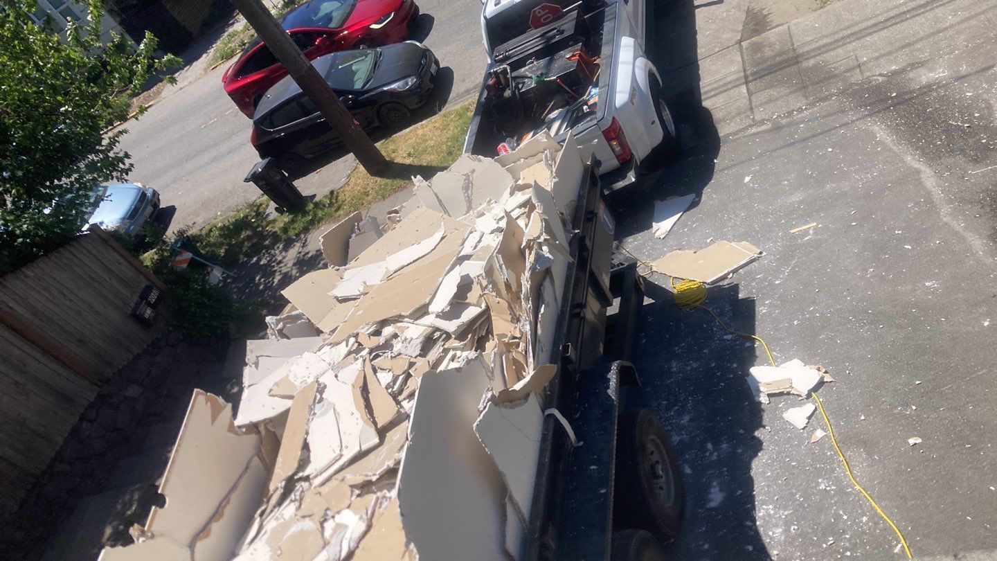 A truck is sitting on the side of the road next to a pile of cardboard.