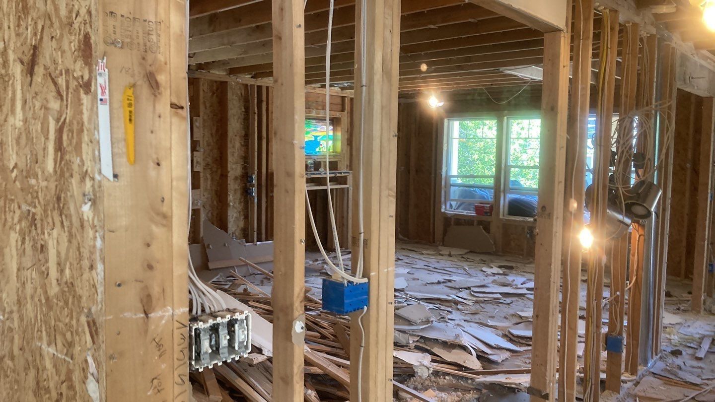 A house is being built with wooden beams and electrical wires hanging from the ceiling.