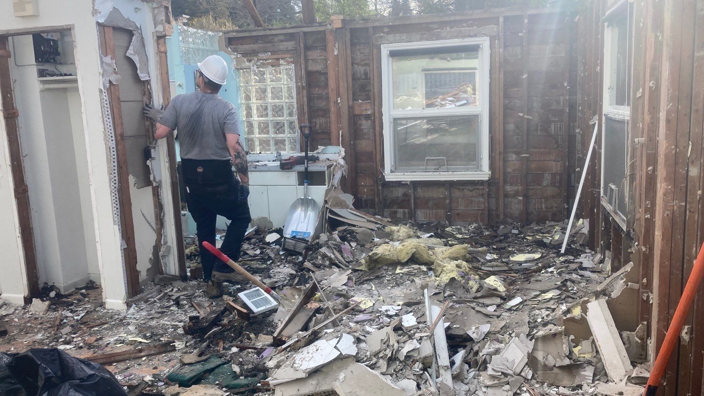 A man is standing in the middle of a house that is being demolished.