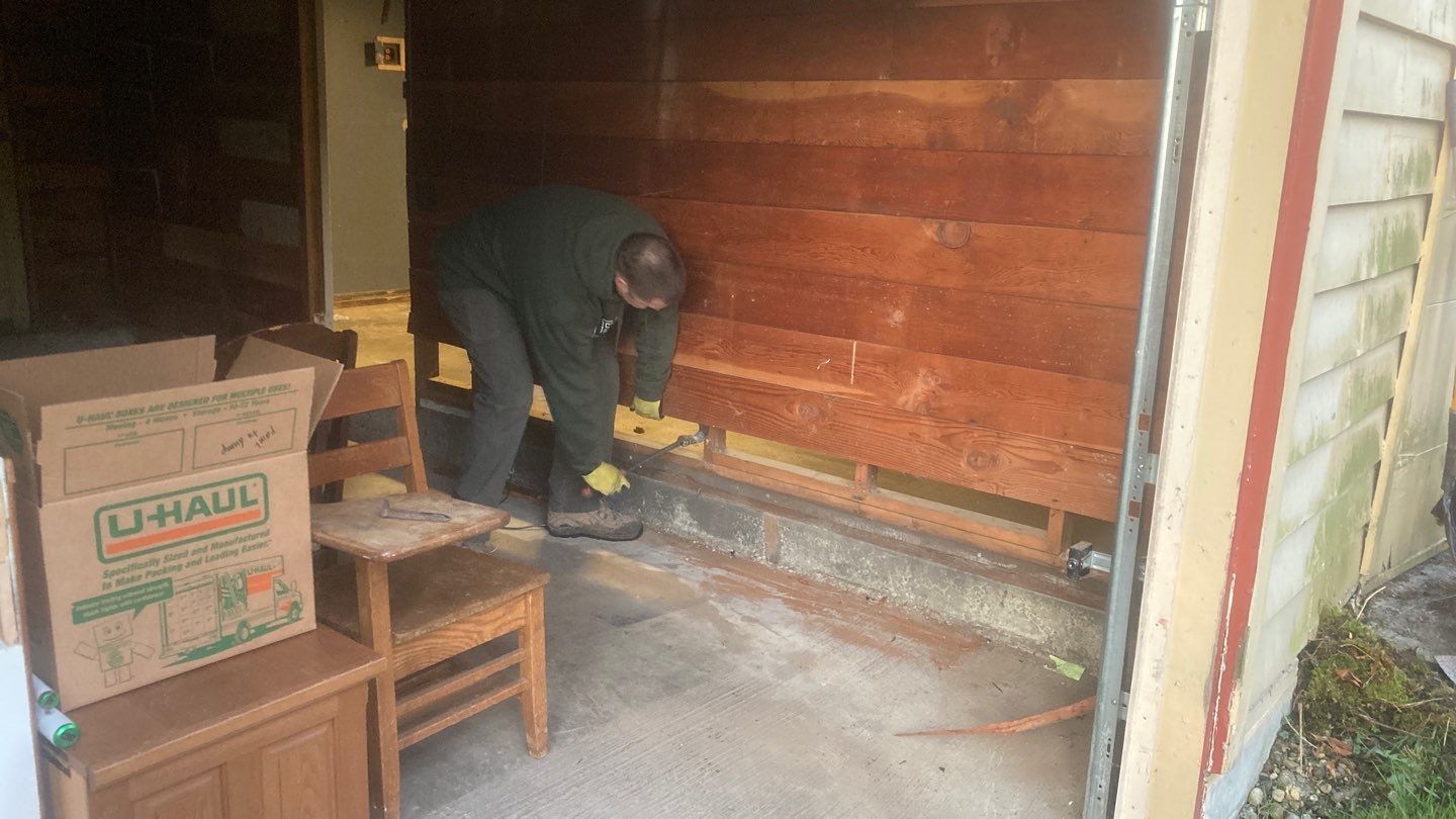 A man is working on a wooden wall in a garage.
