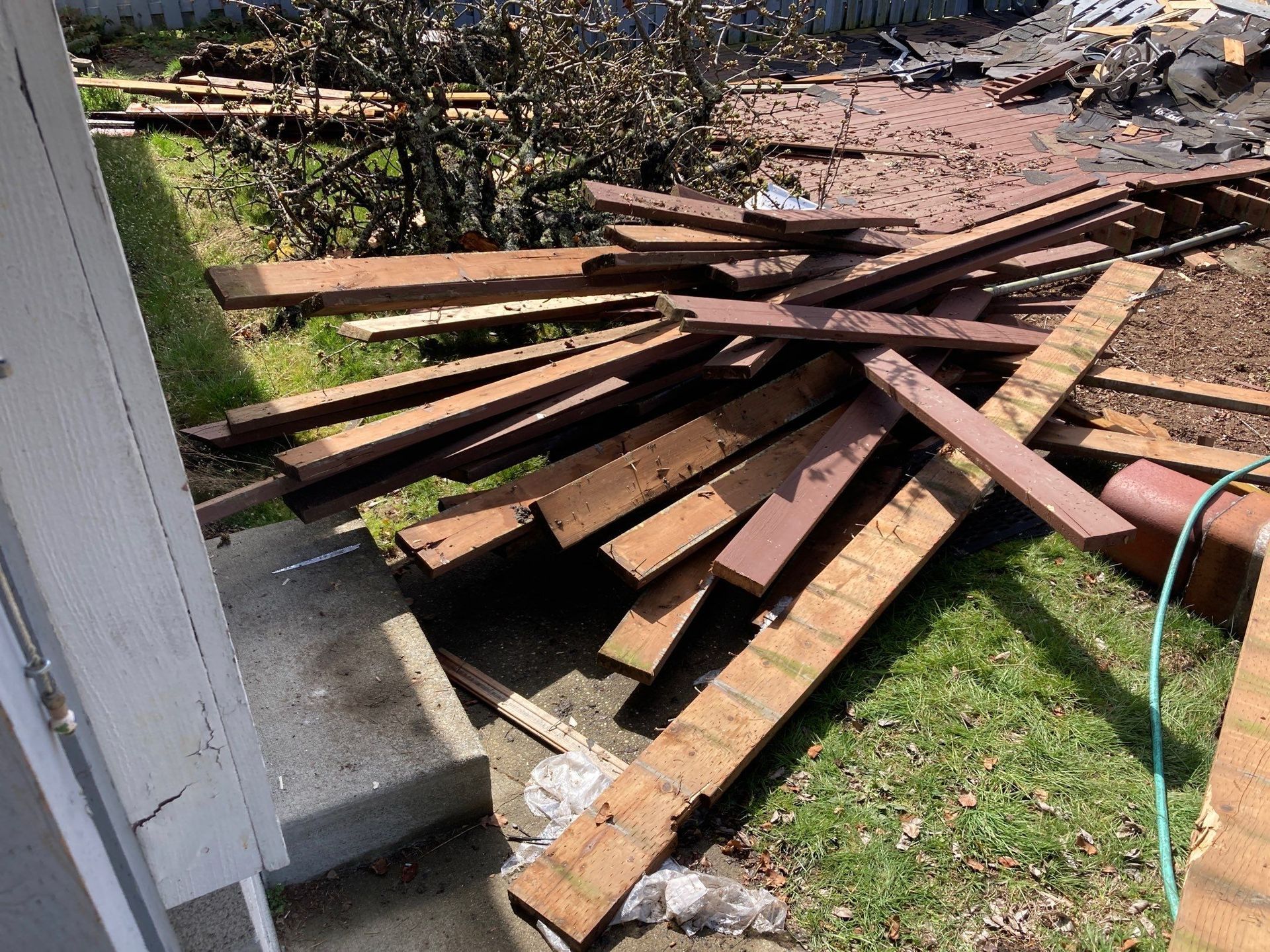 A pile of wood is sitting on the ground in front of a house.