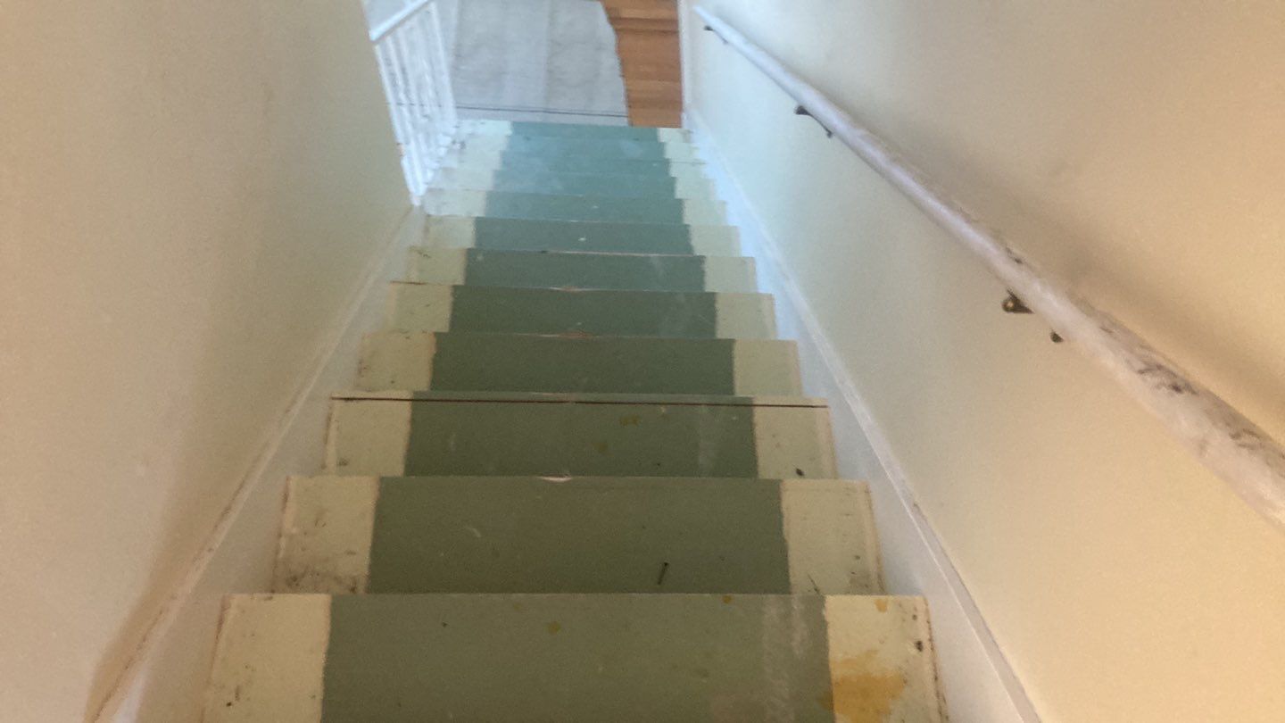 A staircase with a green carpet on the steps and a white railing.
