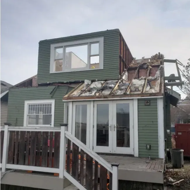 A green house with a roof that is being removed