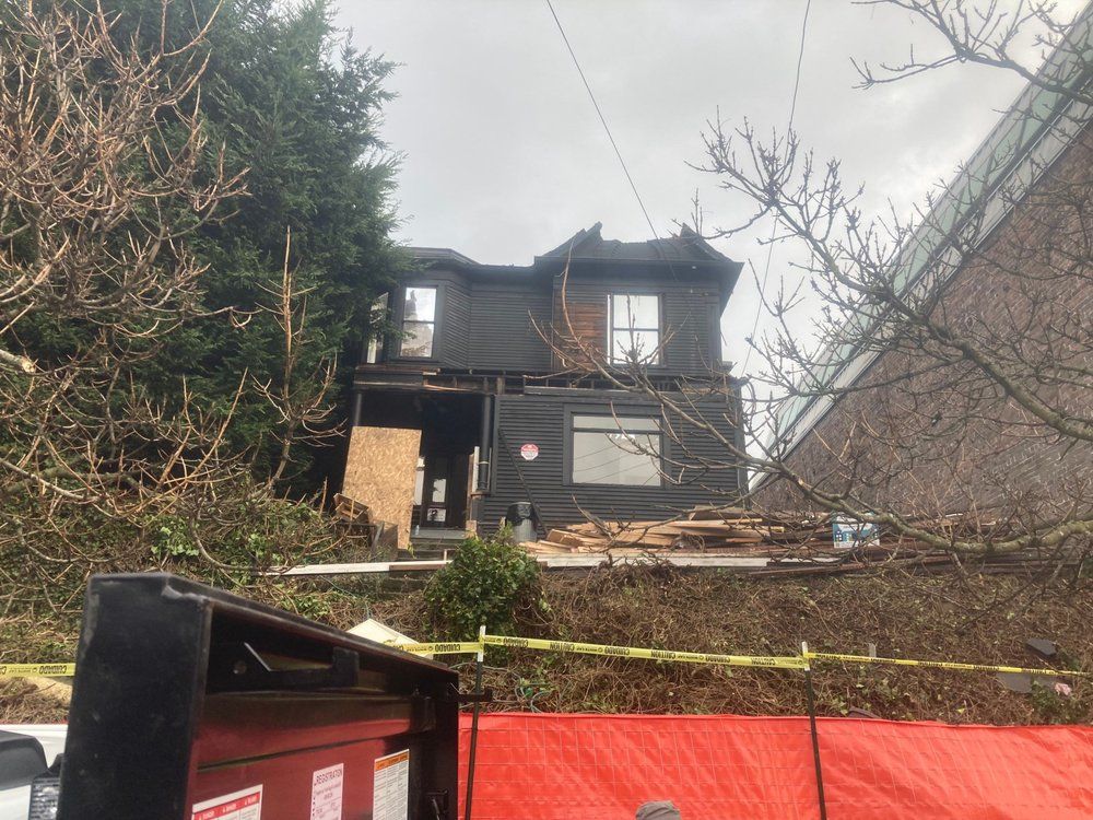 A black house is being demolished and a red tarp is covering it.