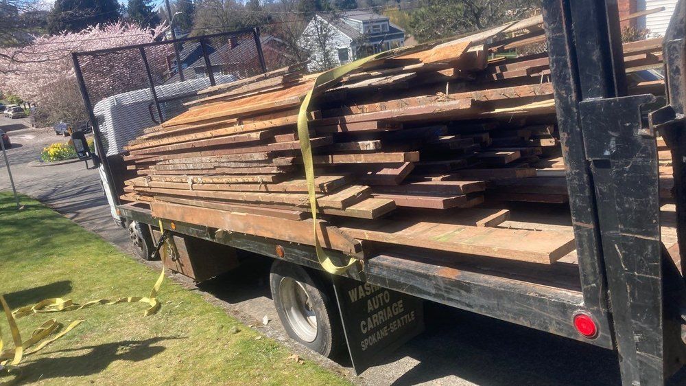 A truck is carrying a pile of wood on the back of it.