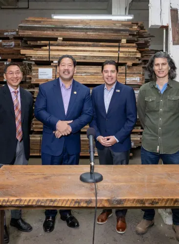 A group of men are standing around a table in front of a microphone.