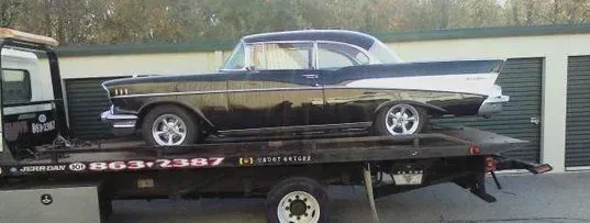 Black classic car on a tow truck