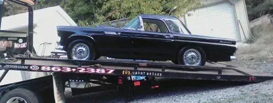A black vintage car on a tow truck