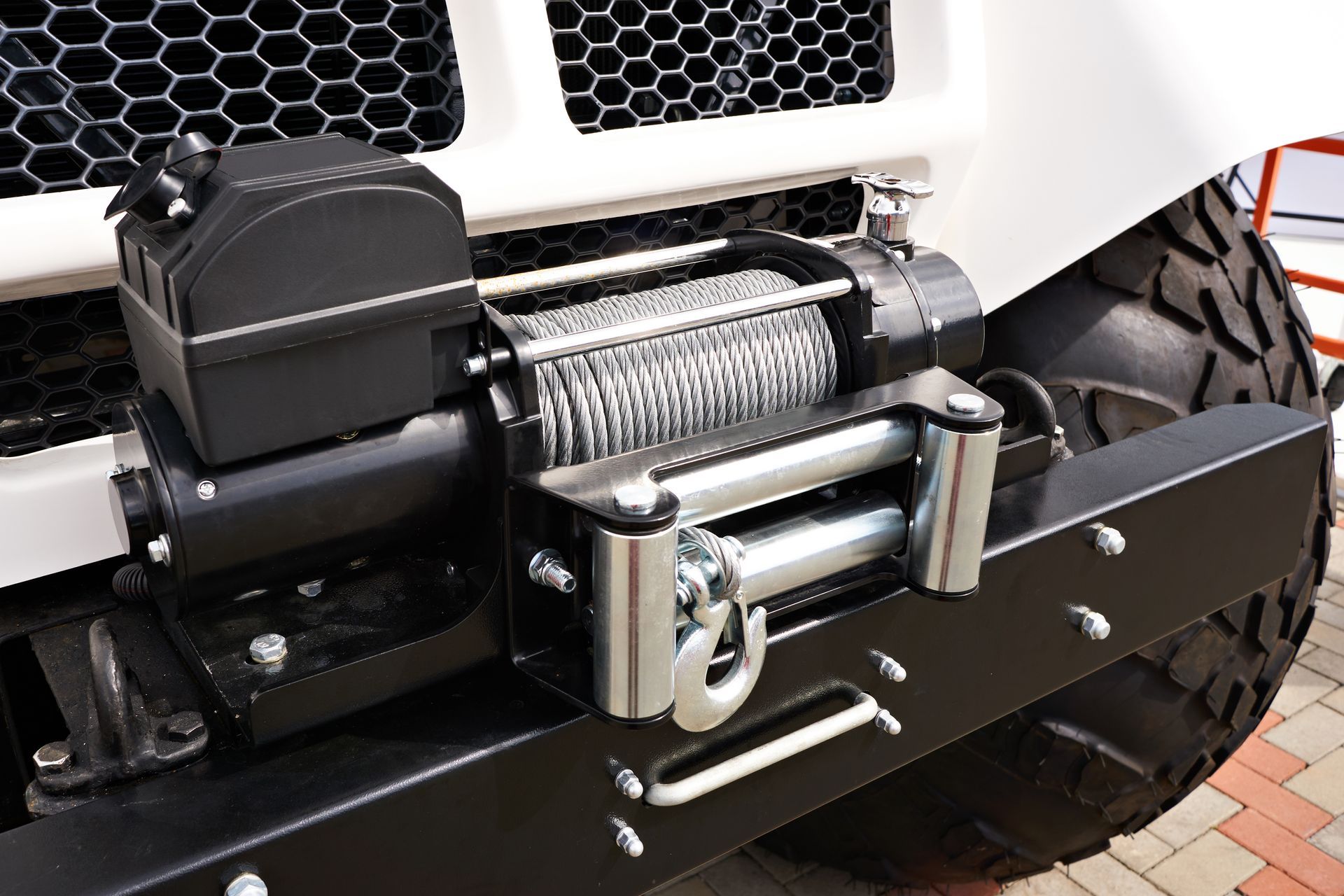 Black winch mounted on a white truck bumper