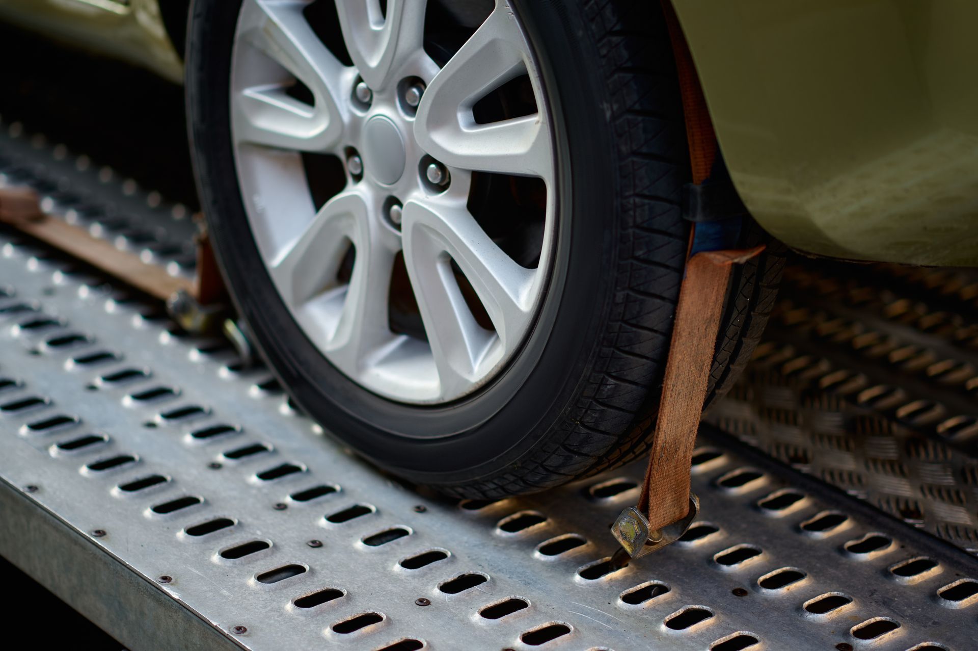 Car tire secured with straps on a tow truck bed