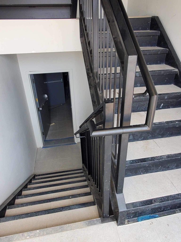 Un escalier avec une rampe en métal et une porte en arrière-plan