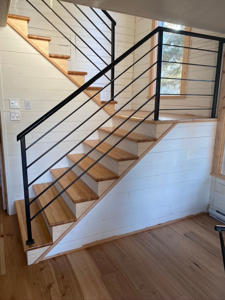 Un escalier en bois avec une rampe noire dans une pièce.