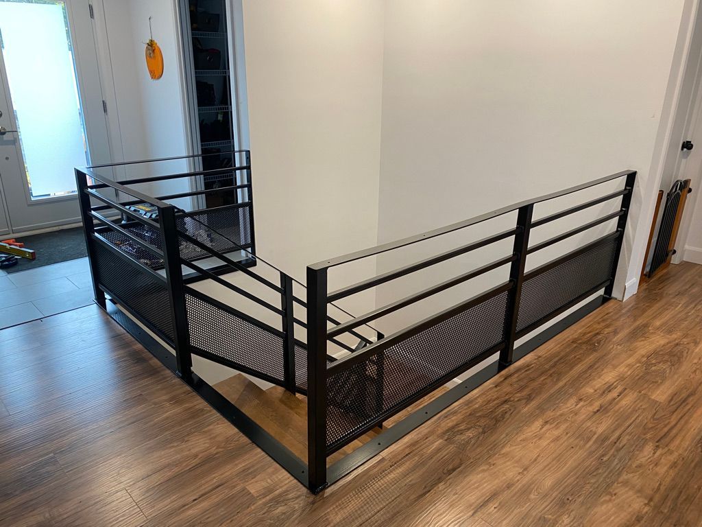 Un escalier avec une rampe noire et un plancher en bois dans une maison.