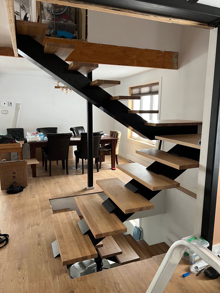 Un escalier en bois dans un salon avec une table et des chaises.