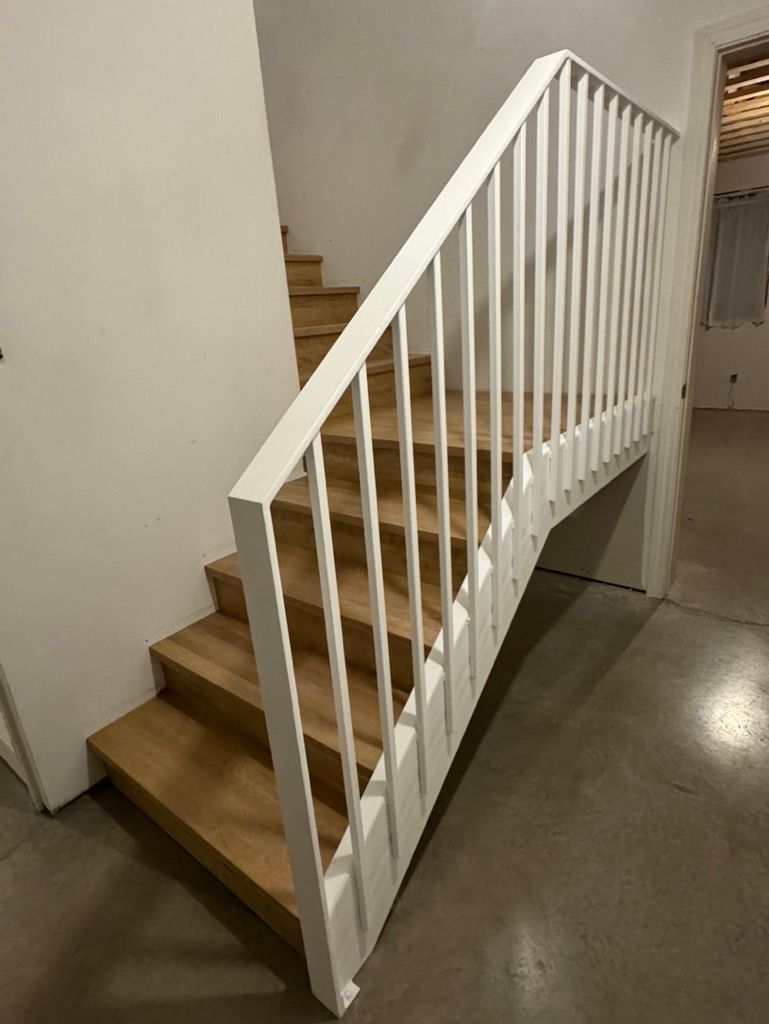 Un escalier en bois avec une rampe blanche dans une pièce.