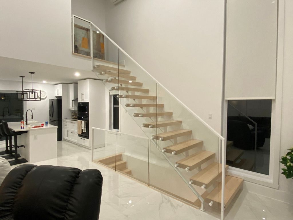 Un salon avec un escalier et une rampe en verre.