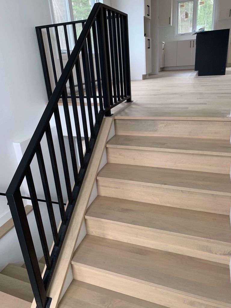 Un escalier en bois avec une rampe noire dans une maison.