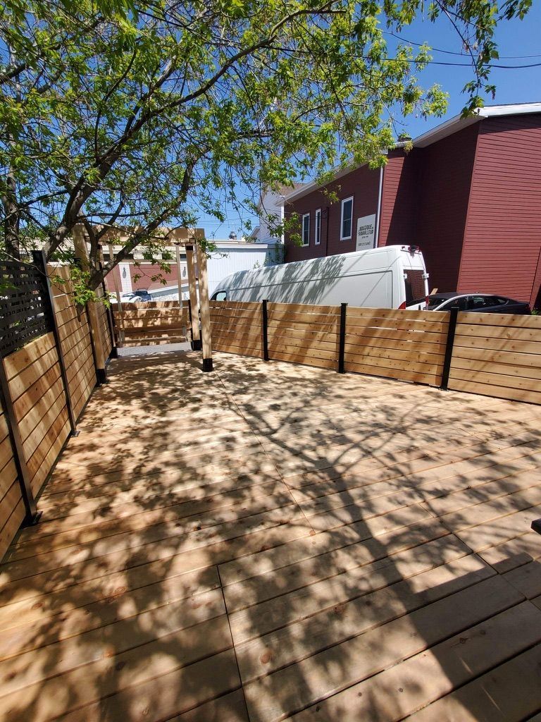 Une terrasse en bois avec une clôture en bois et un bâtiment en arrière-plan.