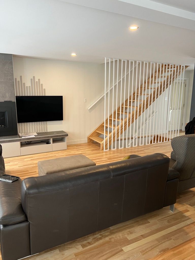 Un salon avec un canapé, une télévision, une cheminée et un escalier.