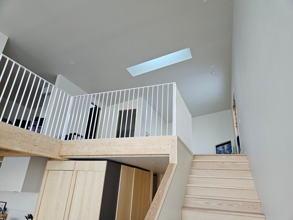 Un escalier en bois menant à un loft avec une rampe blanche.