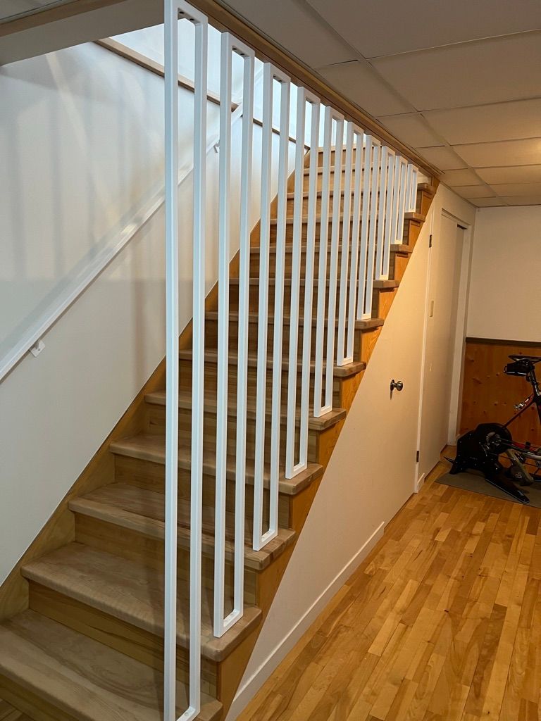 Un escalier en bois avec une rampe blanche dans un couloir.