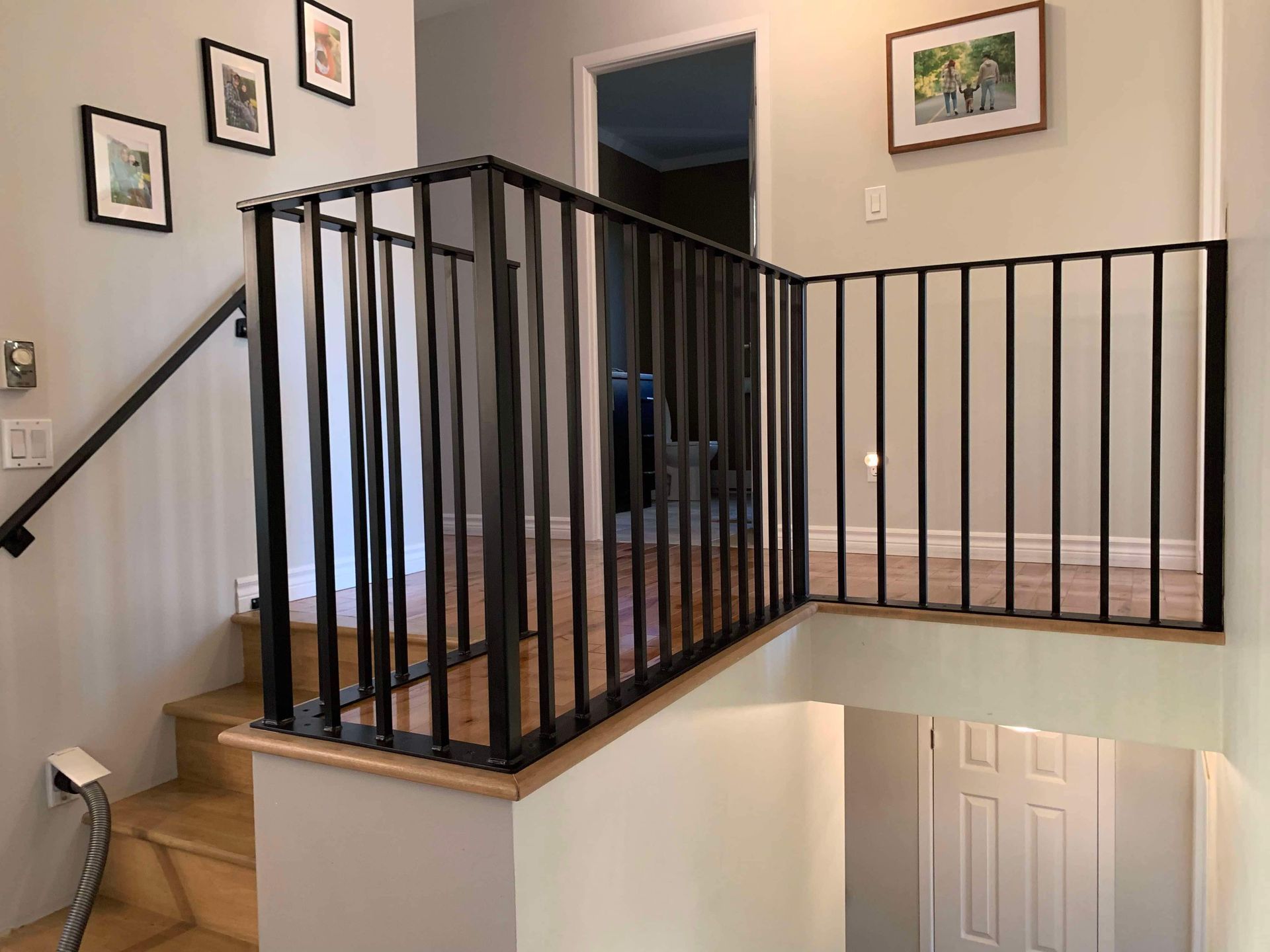 Un escalier avec une rampe noire et des marches en bois dans une maison.